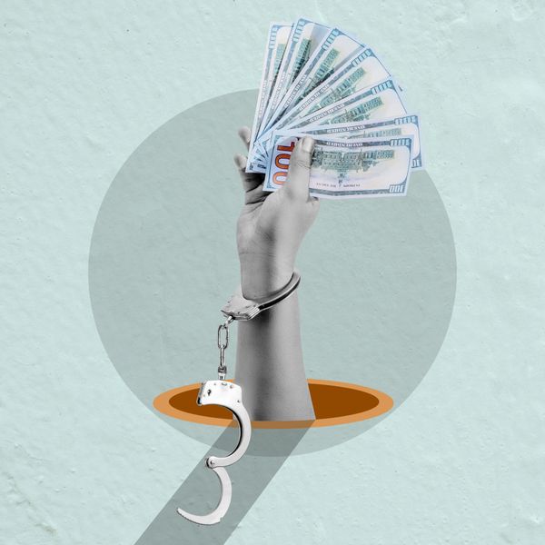 A freed hand holding cash, the handcuff falling open